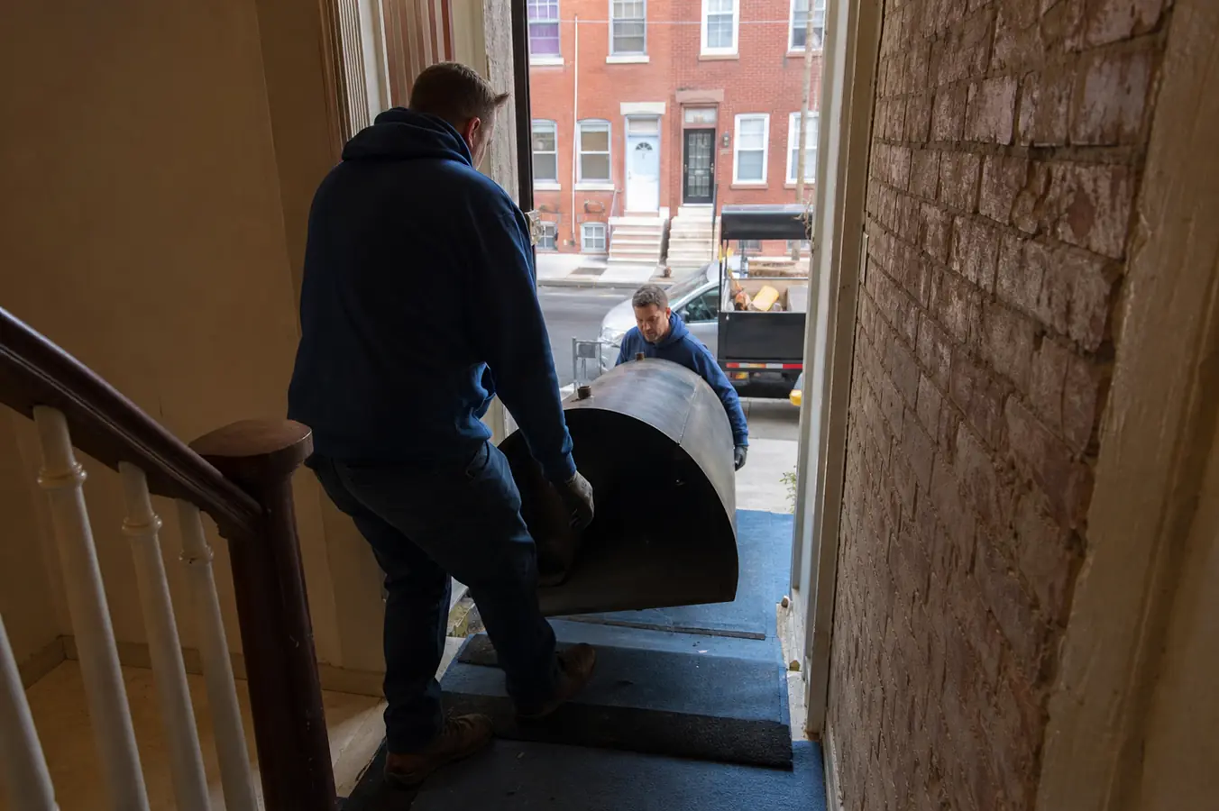 Crew carrying a tank section through a South Philadelphia rowhouse